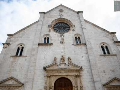 Per raggiungere l�ingresso camminiamo per qualche metro su via della Minerva raggiungendo la vicina piazza omonima. La bianca facciata di stile romanico pugliese presenta un grande rosone centrale sul quale campeggia la statua di Giuditta con la testa di Oloferne. Sotto, invece, una scultura di Ercole si batte con un mostro marino e un leone, simboli delle 12 fatiche